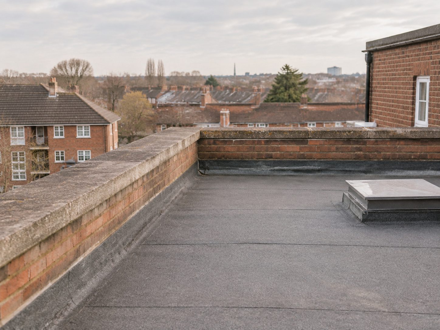 The flat roof and parapet of a residential block