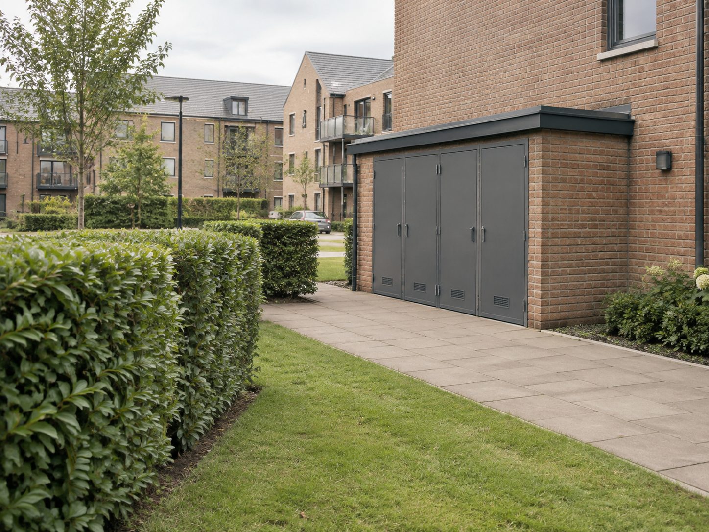 A boundary hedge and bin store at a development