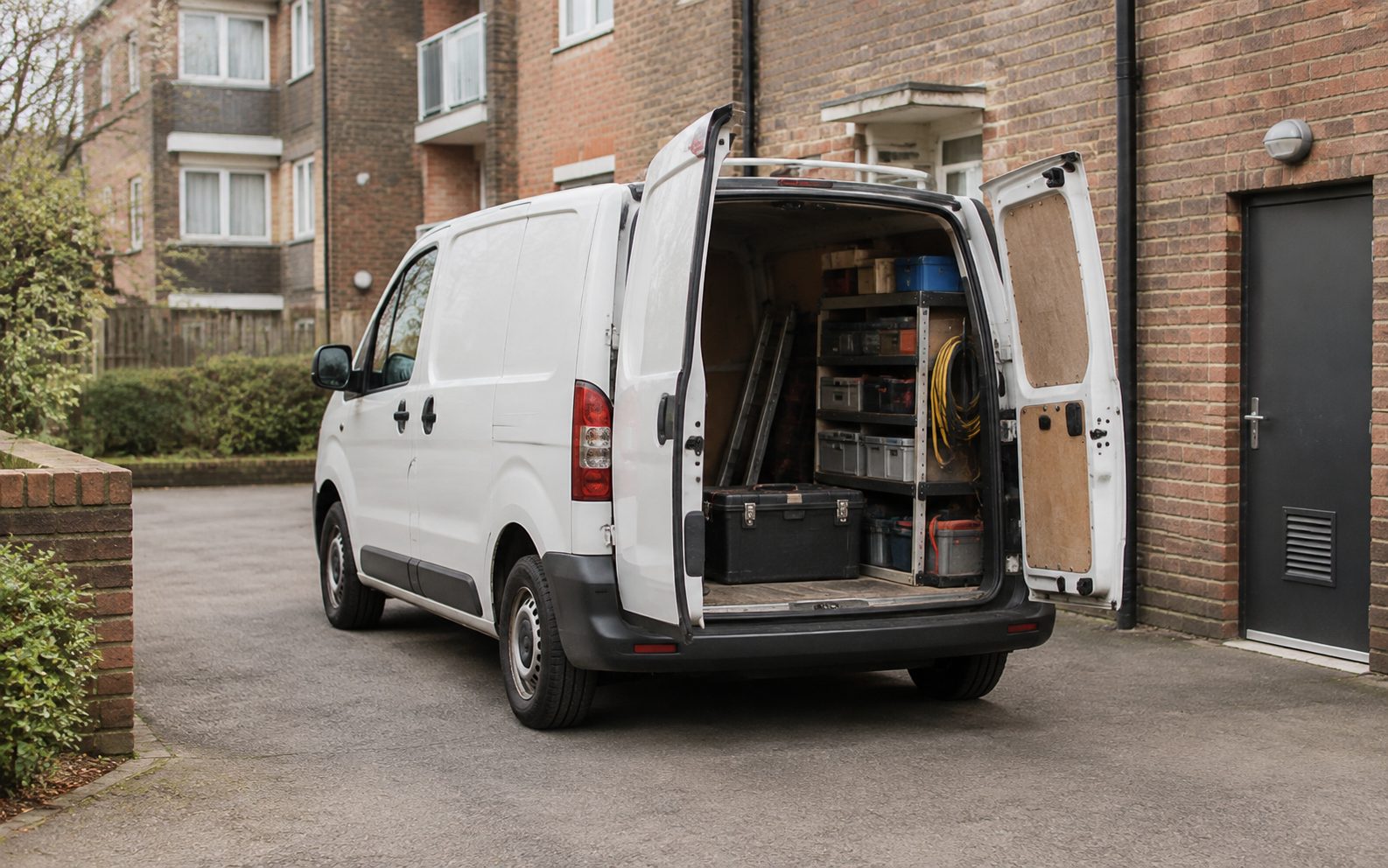 A small trade van at the rear service yard of a block